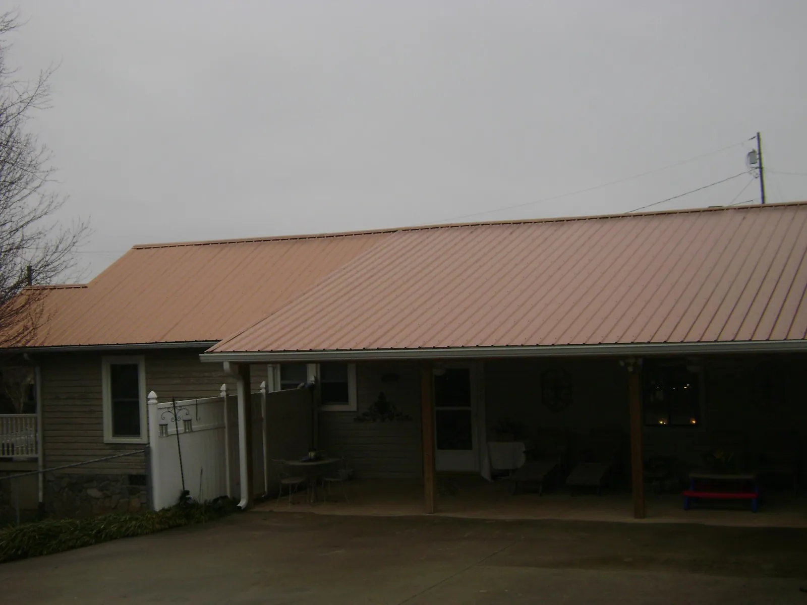 Copper toned metal roof over a wide covered patio in Lacona